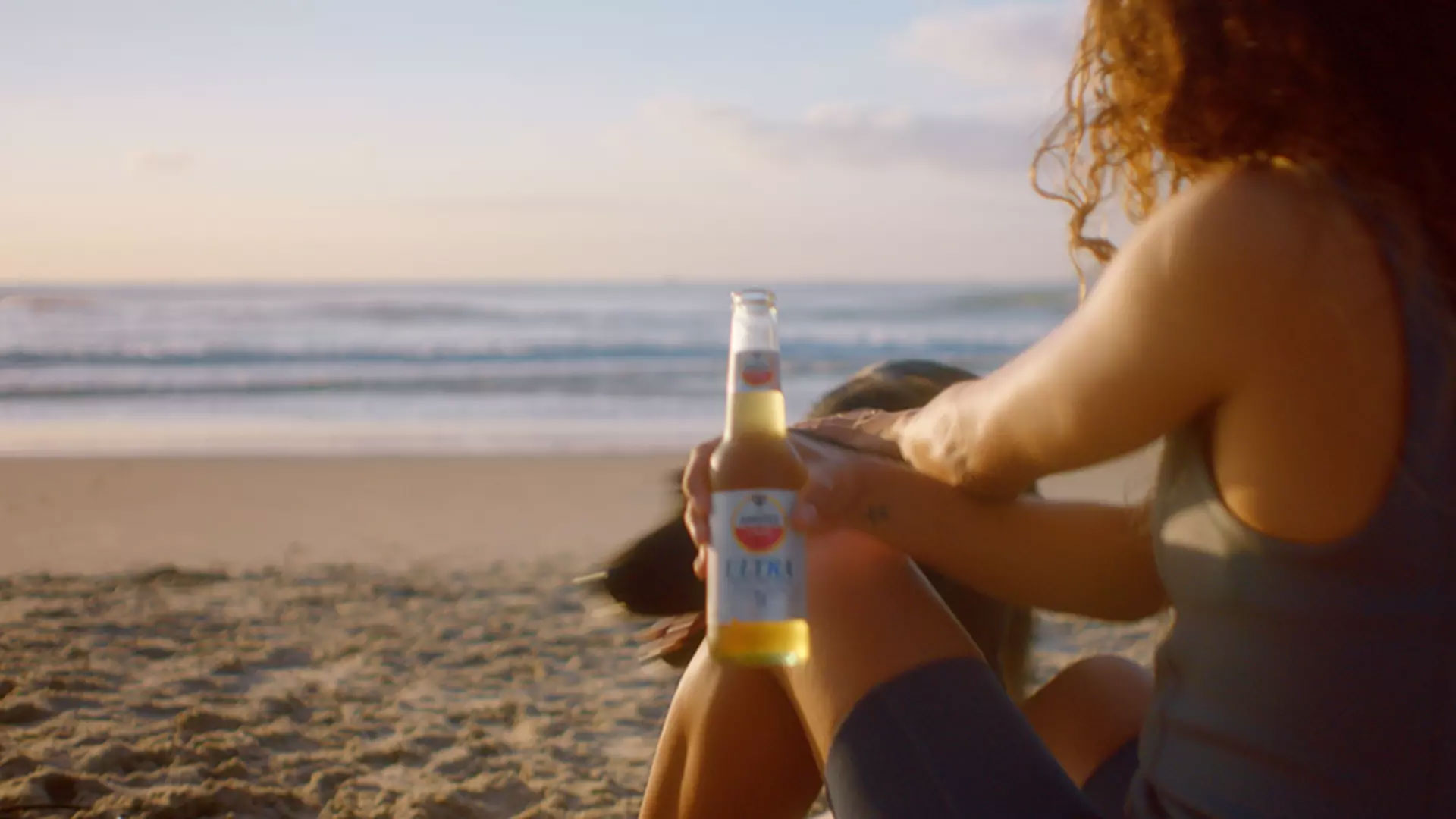 Mulher na praia segurando Amstel Ultra